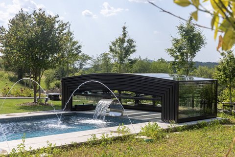 Ein Pool, an dessen Ende eine eingefahrene Poolüberdachung sitzt.